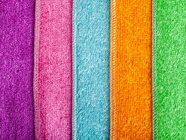 Mikrofaser-Putzlappen in verschiedenen Farben liegen nebeneinander auf dem Tisch.