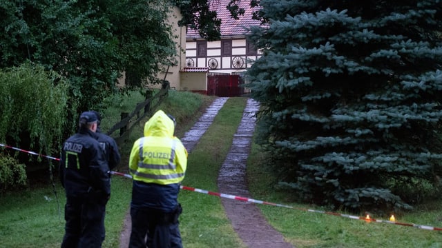 Bauernhof im Hintergrund, davor Bäume, ein Weg und Polizei. Bauernhof im Hintergrund, davor Bäume, ein Weg und Polizei.