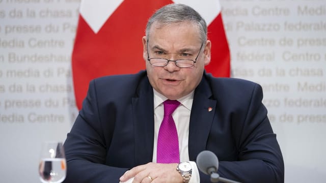 Mann an Medienkonferenz spricht ins Mikro. Mann an Medienkonferenz spricht ins Mikro.