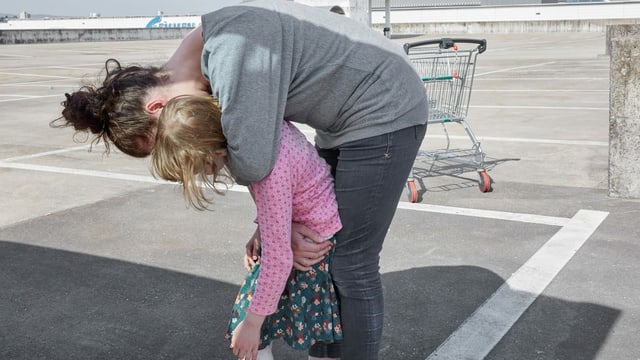 Eine Mutter umarmt ihr Kind von hinten. Eine Mutter umarmt ihr Kind von hinten.