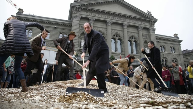 Die Initianten für ein bedingungsloses Grundeinkommen schaufeln 5-Räppler Haufen auf dem Bundesplatz. Die Initianten für ein bedingungsloses Grundeinkommen schaufeln 5-Räppler Haufen auf dem Bundesplatz.
