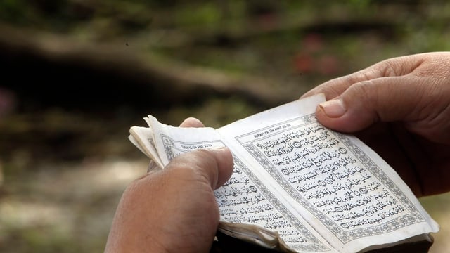 Zwei Hände halten einen Koran. Zwei Hände halten einen Koran.