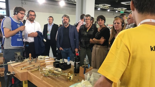 Pliras persunas stattan enturn in baun da lavur nua ch'i vegn reparà instruments. Pliras persunas stattan enturn in baun da lavur nua ch'i vegn reparà instruments.