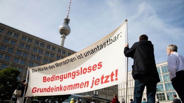 Demonstration in Berlin für ein bedingungsloses Grundeinkommen. Im Vordergrund Demonstranten, im Hintergrund der Berliner Fensehturm.