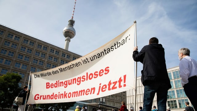 Demonstration in Berlin für ein bedingungsloses Grundeinkommen. Im Vordergrund Demonstranten, im Hintergrund der Berliner Fensehturm. Demonstration in Berlin für ein bedingungsloses Grundeinkommen. Im Vordergrund Demonstranten, im Hintergrund der Berliner Fensehturm.