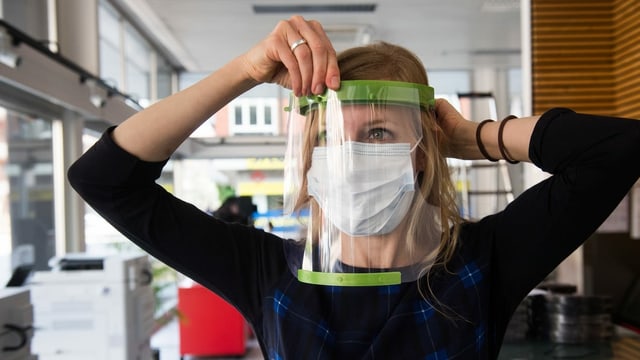 Eine Frau posiert mit einem Schutzvisier aus Plexiglas vor den Augen. Eine Frau posiert mit einem Schutzvisier aus Plexiglas vor den Augen.