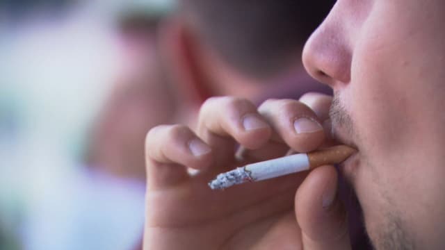 Nahaufnahme Mann mit Zigarette in der Hand vor Gesicht Nahaufnahme Mann mit Zigarette in der Hand vor Gesicht