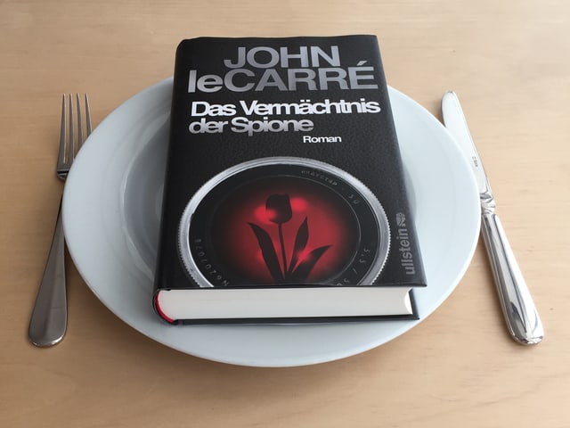 Der Spionageroman «Das Vermächtnis der Spione» von John le Carré auf einem Teller Der Spionageroman «Das Vermächtnis der Spione» von John le Carré auf einem Teller