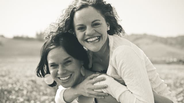 Zwei junge Frauen, die eine trägt die andere auf dem Rücken. Zwei junge Frauen, die eine trägt die andere auf dem Rücken.