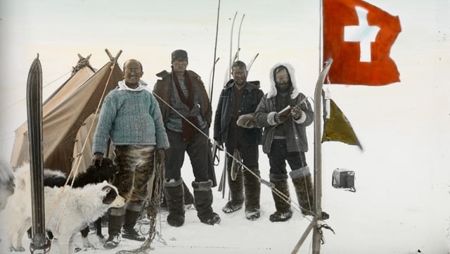 Vier Männer auf dem Eis, dahinter ein Zelt, vorne eine Schweizer Flagge. Vier Männer auf dem Eis, dahinter ein Zelt, vorne eine Schweizer Flagge.
