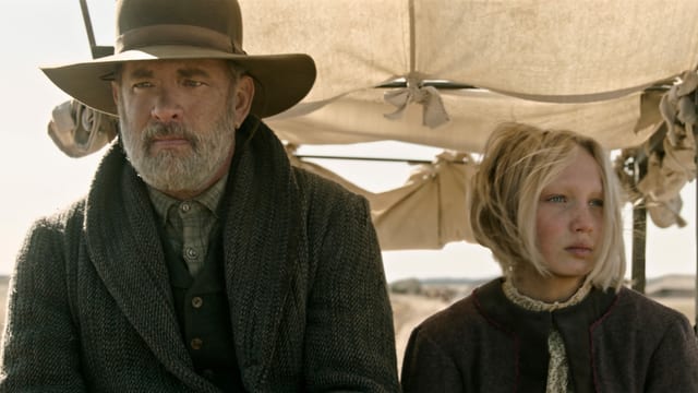 Tom Hanks und Helena Zengel, frontal fotografiert in einer Kutsche. Tom Hanks und Helena Zengel, frontal fotografiert in einer Kutsche.