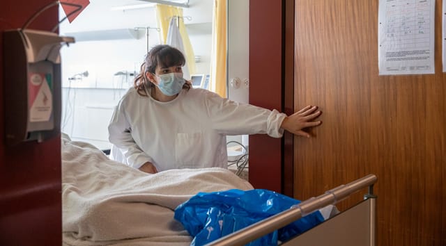 Aline Zehnder öffnet eine Tür. Sie schiebt einen Patienten in ein Zimmer. Aline Zehnder öffnet eine Tür. Sie schiebt einen Patienten in ein Zimmer.