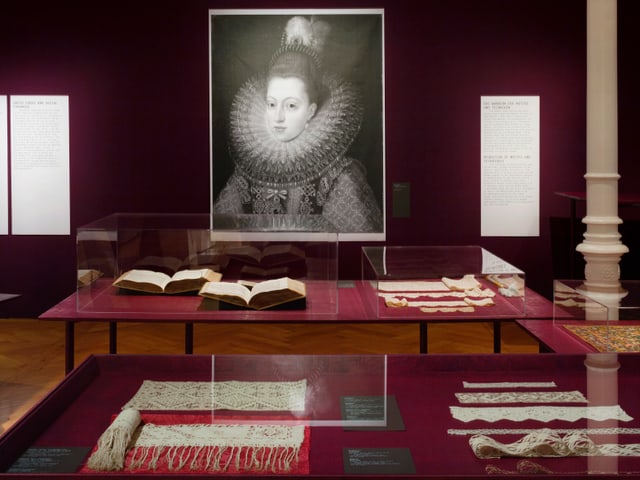 Schwarzweiss-Gemälde einer Dame mit Spitzenkragen, davor Ausstellungsstücke in Vitrinen Schwarzweiss-Gemälde einer Dame mit Spitzenkragen, davor Ausstellungsstücke in Vitrinen