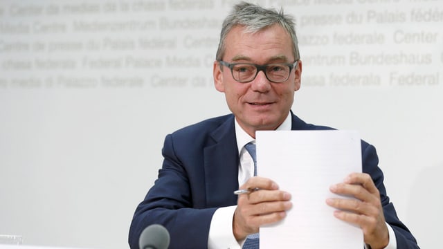 Ruedi Noser sitzt an einem Tisch und hält einen Stapel Papier in den Händen. Ruedi Noser sitzt an einem Tisch und hält einen Stapel Papier in den Händen.