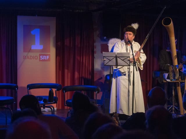 25 Jahre Schnabelweid – mit einem Fest live aus dem Papiersaal in Zürich. Der Abend begeisterte auf vielen Ebenen. Präsent geblieben ist der überraschende und freche Auftritt von Matto Kämpf als Erzengel Gabriel, der Berndeutsch über alle anderen Dialekte stellte und drum Nicht-Berndeutsch-Sprechende, also den «Abschaum», eliminieren wollte. 25 Jahre Schnabelweid – mit einem Fest live aus dem Papiersaal in Zürich. Der Abend begeisterte auf vielen Ebenen. Präsent geblieben ist der überraschende und freche Auftritt von Matto Kämpf als Erzengel Gabriel, der Berndeutsch über alle anderen Dialekte stellte und drum Nicht-Berndeutsch-Sprechende, also den «Abschaum», eliminieren wollte.