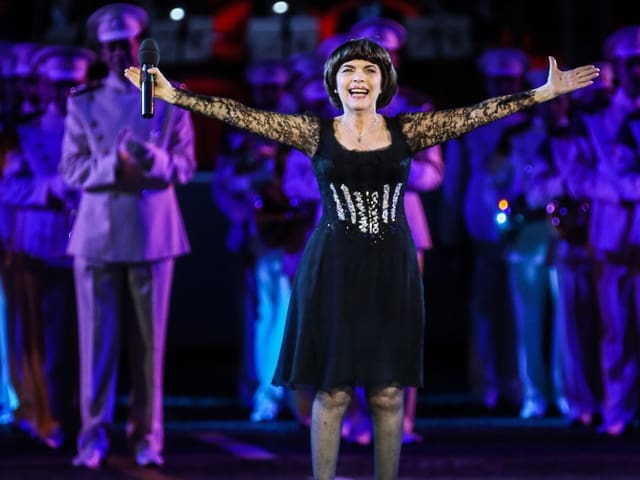 Mireille während Konzert mit weit ausgebreiteten Armen auf der Bühne stehend. Mireille während Konzert mit weit ausgebreiteten Armen auf der Bühne stehend.
