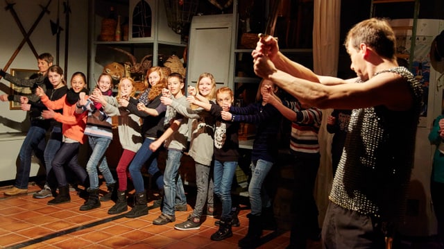 Eine Schulklasse ist auf einer Theatertour im Historischen Museum. Ein Schauspieler zeigt vor, wie Ritter mit dem Schwert kämpfen. Eine Schulklasse ist auf einer Theatertour im Historischen Museum. Ein Schauspieler zeigt vor, wie Ritter mit dem Schwert kämpfen.
