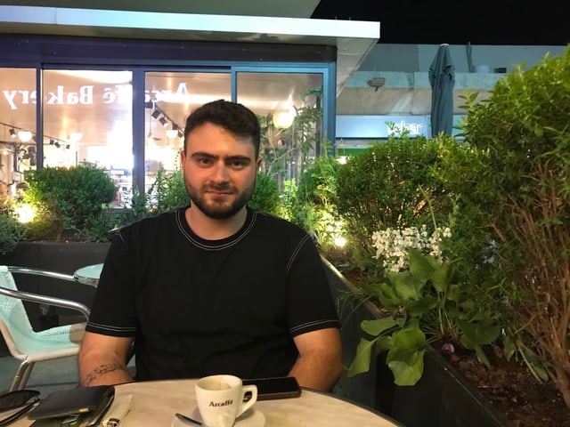 Mansour sitzt an einem Tisch. Mansour sitzt an einem Tisch.