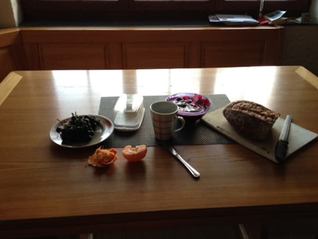 Früchte, Müesli, Tasse und Brot auf dem Tisch.