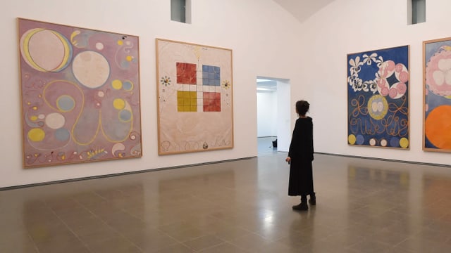 Eine Frau schaut sich eine Ausstellung mit der Kunst von Hilma Af Klint an. Eine Frau schaut sich eine Ausstellung mit der Kunst von Hilma Af Klint an.