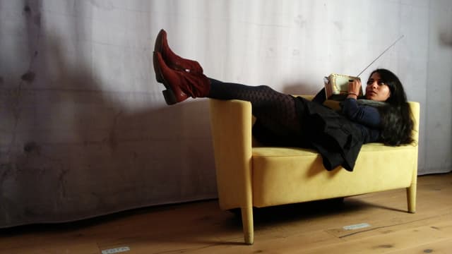 Reena liegt mit Retroradio in der Hand auf einem gelben Sofa Reena liegt mit Retroradio in der Hand auf einem gelben Sofa