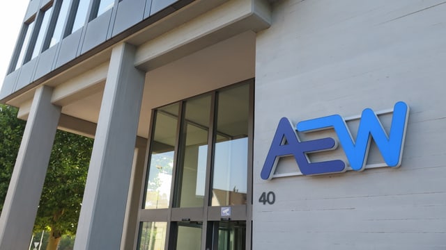 Ein Hochhaus aus Beton mit einem blauen Schriftzug drauf: AEW Ein Hochhaus aus Beton mit einem blauen Schriftzug drauf: AEW