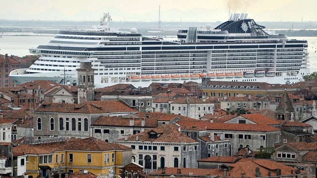 Ein Kreuzfahrtschiff im Hintergrund überragt die Stadtsilhouette von Venedig Ein Kreuzfahrtschiff im Hintergrund überragt die Stadtsilhouette von Venedig