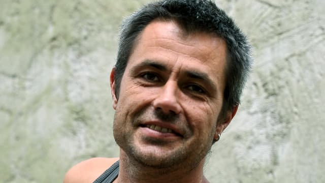 Ein braungebrannter junger Mann mit Ohrring lacht in die Kamera. Ein braungebrannter junger Mann mit Ohrring lacht in die Kamera.