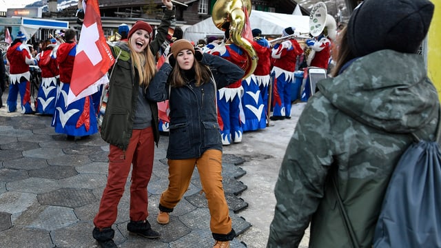 Zwei Frauen und im Hintergrund eine Guggenmusik, am Weltcup Adelboden Zwei Frauen und im Hintergrund eine Guggenmusik, am Weltcup Adelboden