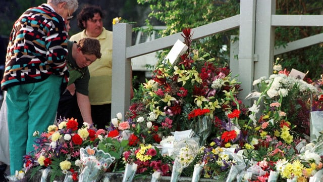 Menschen legen Blumen zum Gedenken hin Menschen legen Blumen zum Gedenken hin