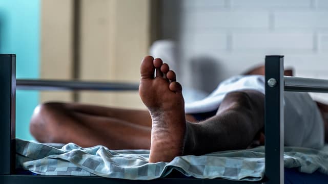 Auf einem Bett liegende Person in einem Empfangszentrum Auf einem Bett liegende Person in einem Empfangszentrum