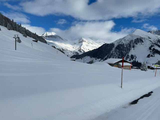 Schneelandschaft und besonnte Berge im Hintergrund.