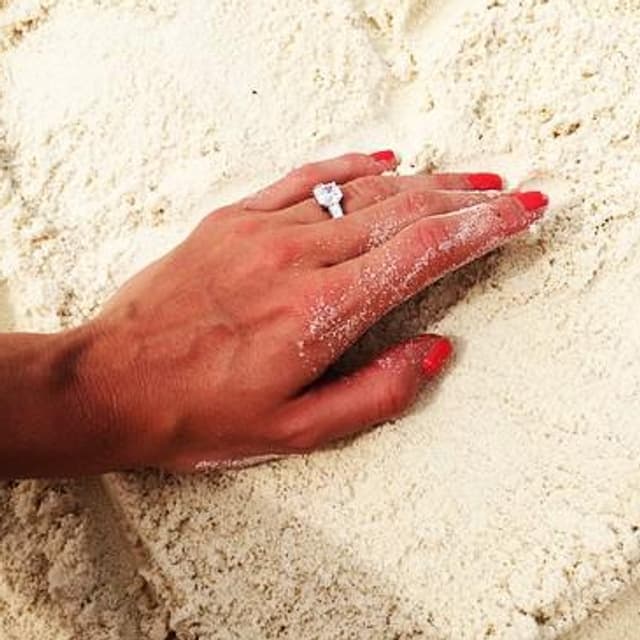 Eine Hand mit Verlobungsring in einem Herz aus Sand. Eine Hand mit Verlobungsring in einem Herz aus Sand.