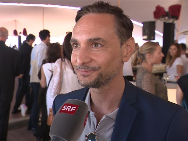 Mann ssteht im Zelt und gibt ein Interview. Mann ssteht im Zelt und gibt ein Interview.