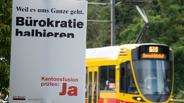 Auf einem weissen Plakat steht «Bürokratie halbieren. Kantonsfusion prüfen: Ja» Auf einem weissen Plakat steht «Bürokratie halbieren. Kantonsfusion prüfen: Ja»