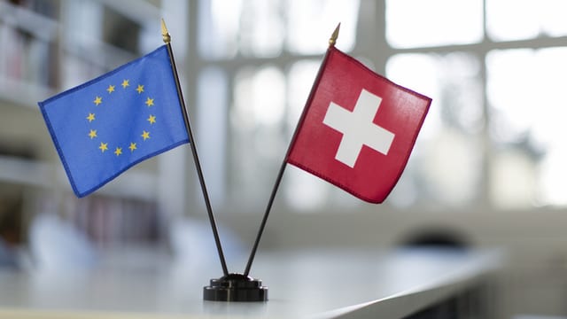 Kleine Fahnen von der EU und der Schweiz auf einem Tisch Kleine Fahnen von der EU und der Schweiz auf einem Tisch