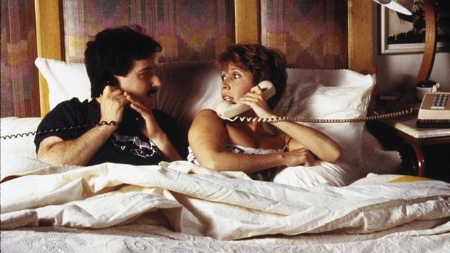 Ein Paar liegt im Bett. Beide haben einen Telefonhörer in der Hand. Ein Paar liegt im Bett. Beide haben einen Telefonhörer in der Hand.