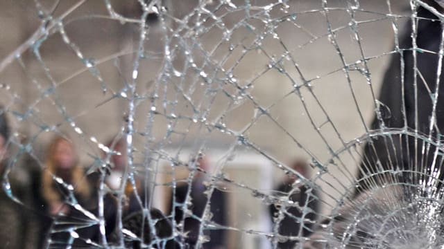 Zersplitterte Scheiben, dahinter Menschen Zersplitterte Scheiben, dahinter Menschen