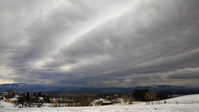 Wellenförmige Wolken über winterlicher Landschaft.