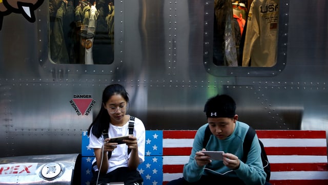 Zwei Jugendliche auf einer Bank im US-Look in einer Pekinger Mall Zwei Jugendliche auf einer Bank im US-Look in einer Pekinger Mall
