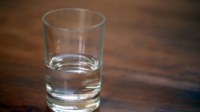 Ein halbvolles Glas steht auf einem Tisch. Ein halbvolles Glas steht auf einem Tisch.
