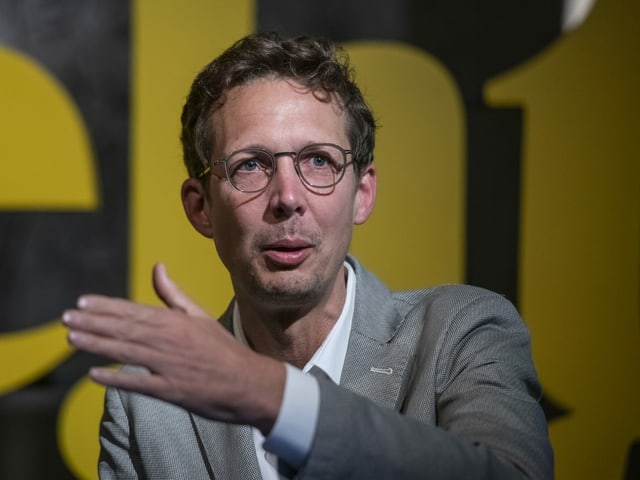 Mann in Anzug und Brille spricht Mann in Anzug und Brille spricht