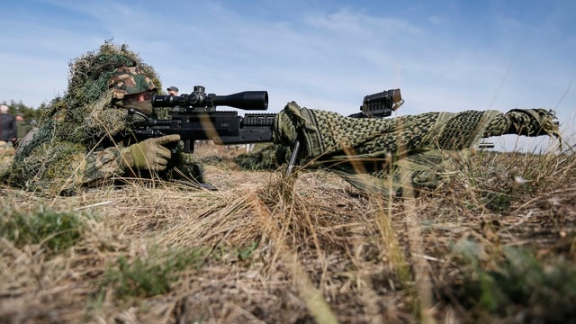 Ein Scharfschütze mit Gewehr auf dem Boden liegend. Ein Scharfschütze mit Gewehr auf dem Boden liegend.