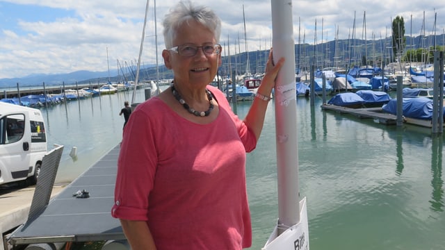 Frau steht am Seeufer, im Hintergrund ein Hafen. Frau steht am Seeufer, im Hintergrund ein Hafen.