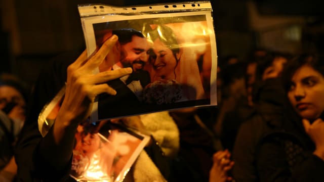 Menschen bei einer Demonstration. Einer hält ein Foto mit einem Ehepaar drauf. Menschen bei einer Demonstration. Einer hält ein Foto mit einem Ehepaar drauf.