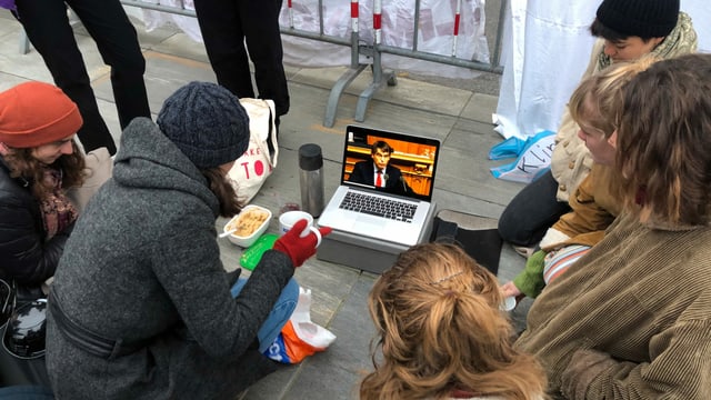 Junge Menschen sitzen am Boden rund um einen Laptop. Junge Menschen sitzen am Boden rund um einen Laptop.