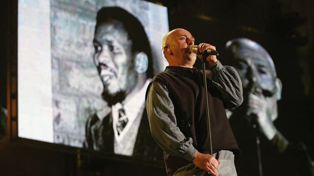 Peter Gabriel auf einer Bühne. Er singt. Peter Gabriel auf einer Bühne. Er singt.
