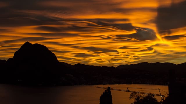 Blick von Norden auf den San Salvatore, der von wilden, gold-gelben Wolken umgeben ist. Blick von Norden auf den San Salvatore, der von wilden, gold-gelben Wolken umgeben ist.