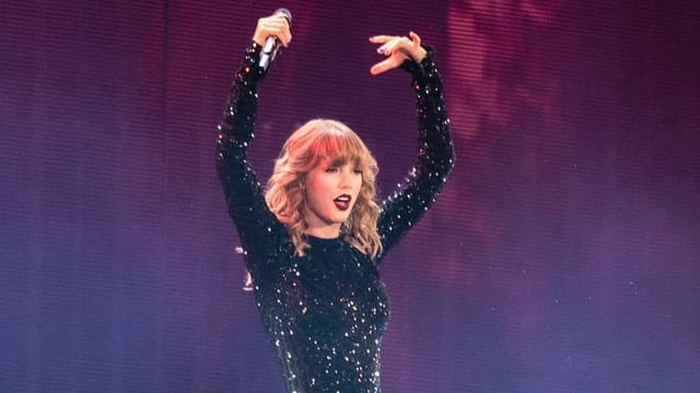Taylor Swift hält die Hände hoch. Taylor Swift hält die Hände hoch.