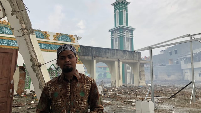 Imam vor zerstörter Moschee. Imam vor zerstörter Moschee.